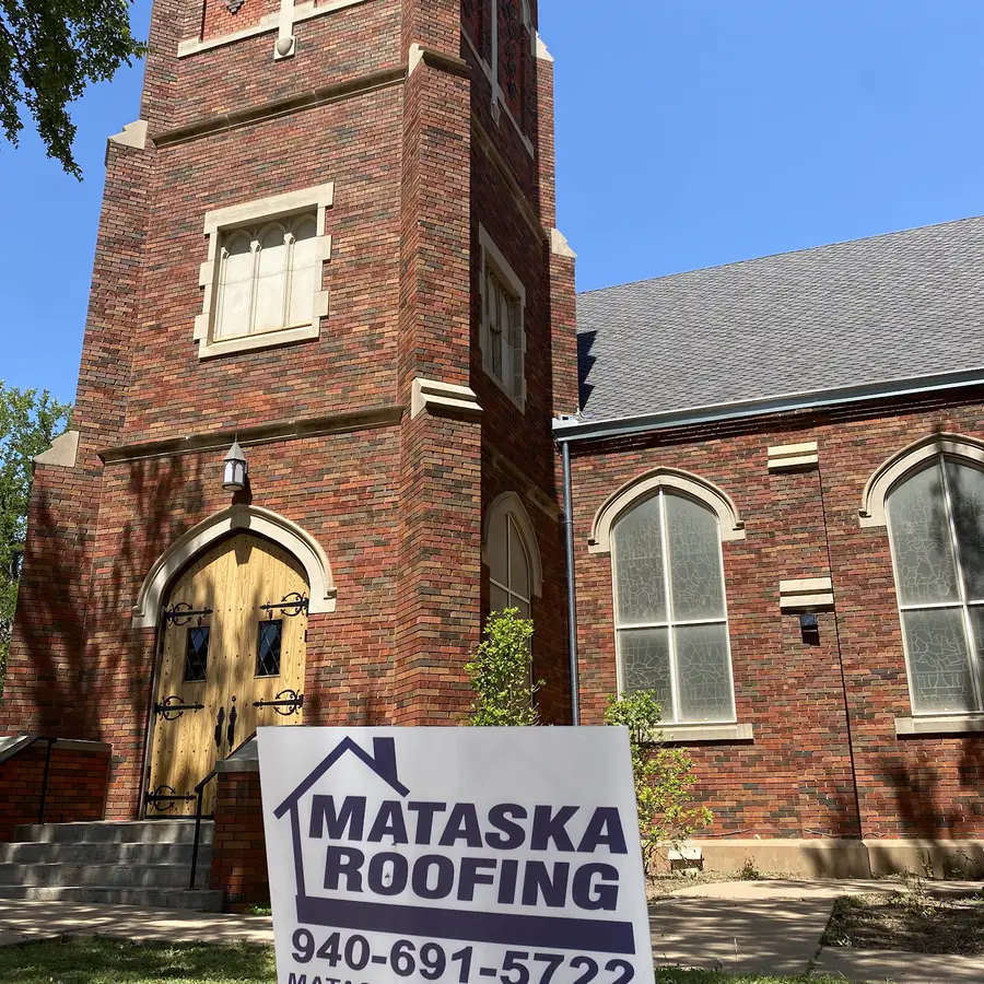 A red brick church in Wichita Falls with a Mataska Roofing yard sign out front during a re-roof.