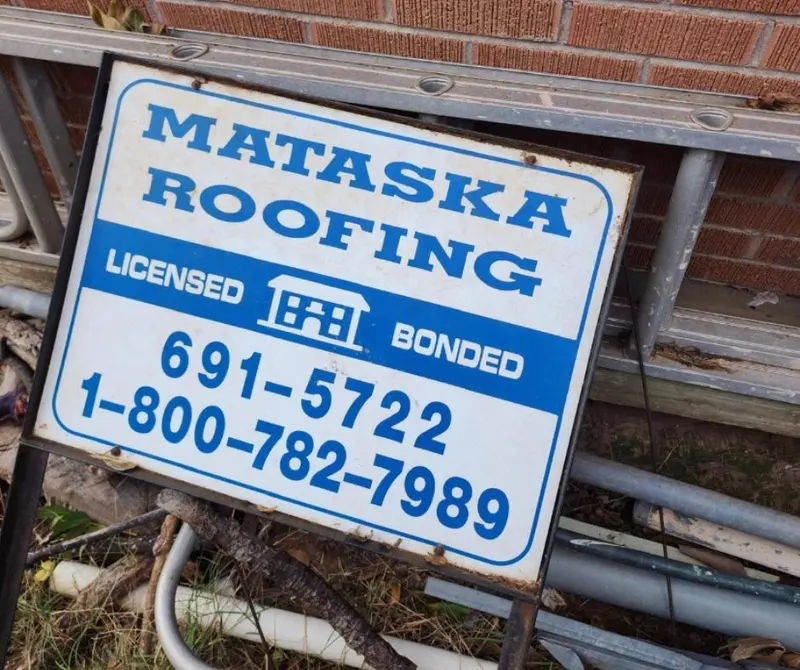 A weathered old blue and white Mataska Roofing yard sign reading Licensed, Bonded, 691-5722 and 1-800-782-7989.