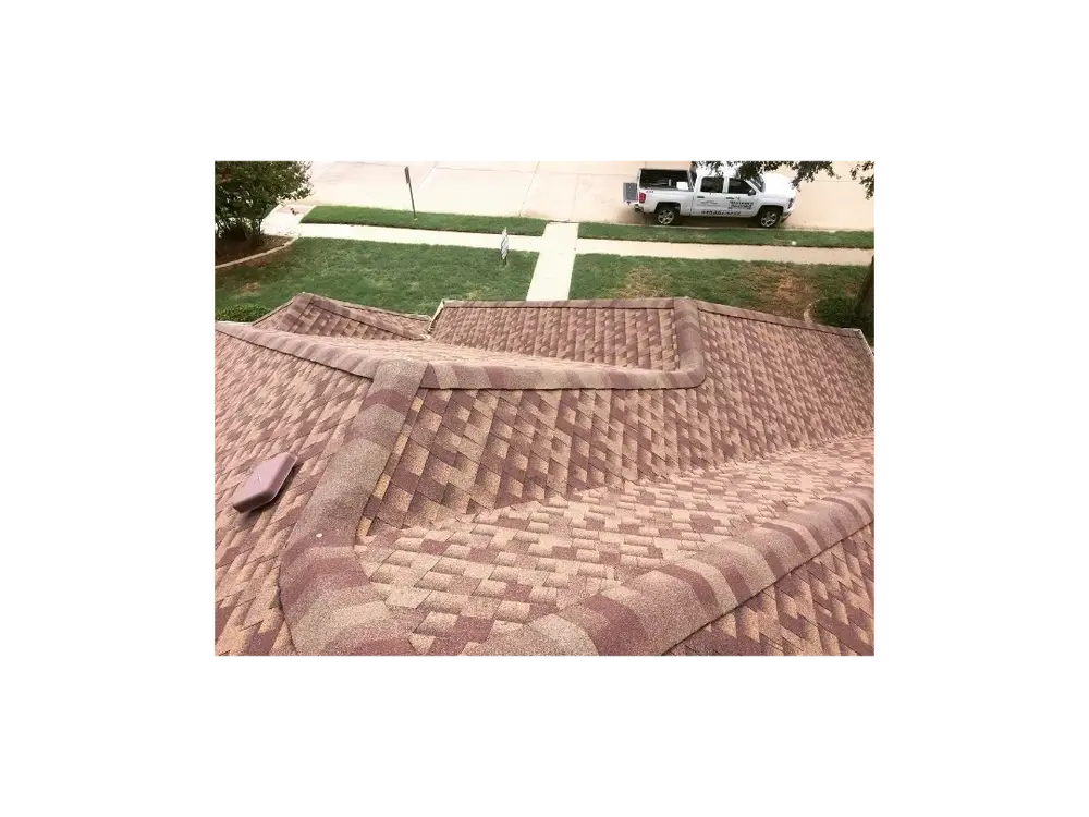 Close view of a brown shingle roof ridge, with a white Mataska pickup parked on the street below.